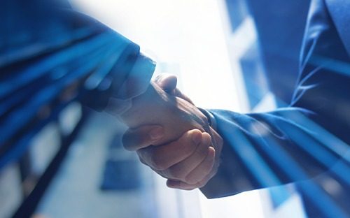 Poignée de main entre deux professionnels en costume dans un environnement lumineux