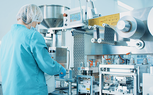 Opérateur en salle propre surveillant une machine de production pharmaceutique équipée de conduites et d’équipements de process