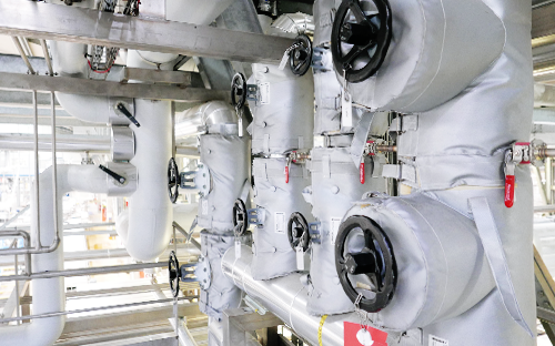 Réseau de tuyauteries vapeur isolées avec vannes manuelles et équipements de mesure en environnement industriel