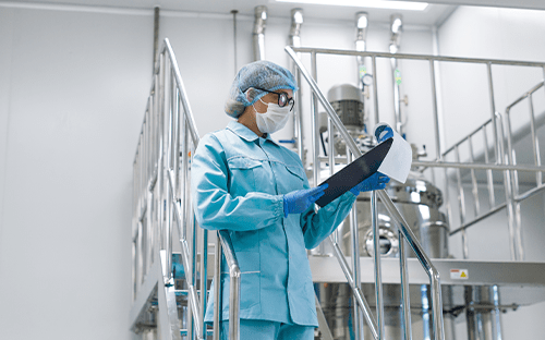 Tecnico in sala industriale controllata che consulta un fascicolo sulla qualità vicino alle apparecchiature di processo termico