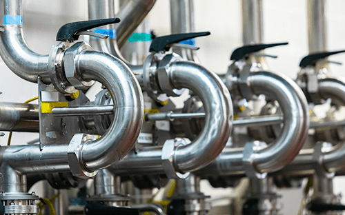 Stainless steel pipe loops with aligned manual valves illustrating installation constraints on a process line