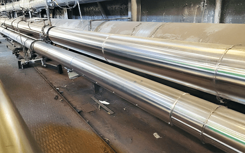 Длинные промышленные трубопроводы из нержавеющей стали, выровненные и изолированные, предназначенные для транспортировки пара в технической установке