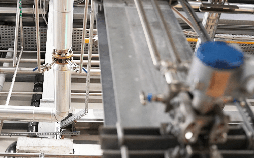 Industrial installation with differential pressure flow meter and primary element mounted on an insulated vertical pipe