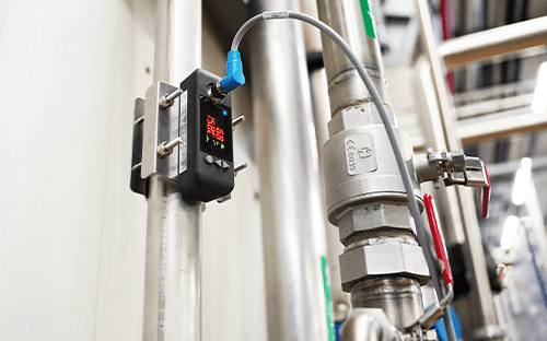 Clamp-on ultrasonic flow meter attached to a pipe with an external sensor measuring flow without contact with the fluid