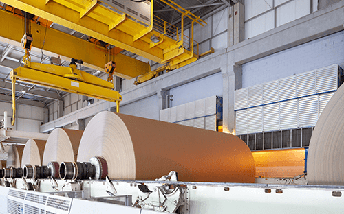 Industrial paper manufacturing facility with large rolls being unwound on an automated production line