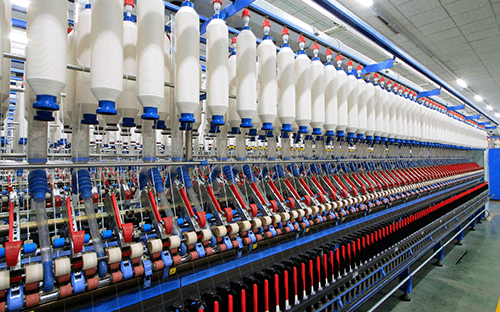 Automated textile production line with aligned spindles and spools, driven by motors on an industrial machine