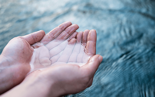 Hands collecting clear water in motion, illustrating a natural liquid fluid and its physical characteristics