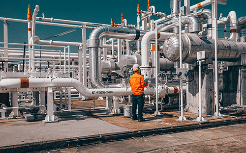 Endüstriyel boru tesisatlarında tesislerin kontrolü ve bakımı için çalışan, kişisel koruyucu ekipmanla donatılmış teknisyen