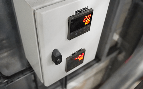 Regolatore di temperatura industriale montato in armadio elettrico con display digitale rosso che indica il valore di riferimento e la misura