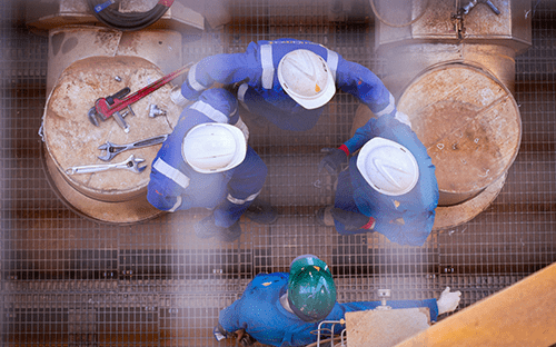Aerial view of technicians wearing helmets working on industrial tanks during a maintenance operation