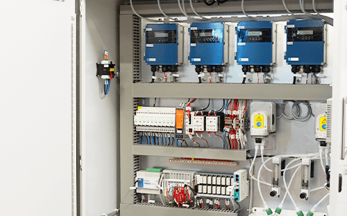 Interior do armário de análise de gases com módulos azuis e componentes elétricos integrados