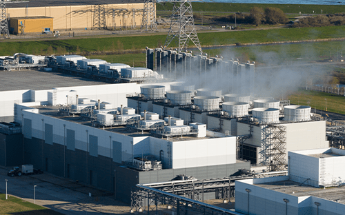 Aerial view of a data center with cooling towers and steam plumes