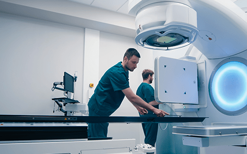 Medizinisches Fachpersonal bereitet eine Strahlentherapieausrüstung im Behandlungsraum vor und veranschaulicht dabei die Rolle des Strahlenschutzbeauftragten.