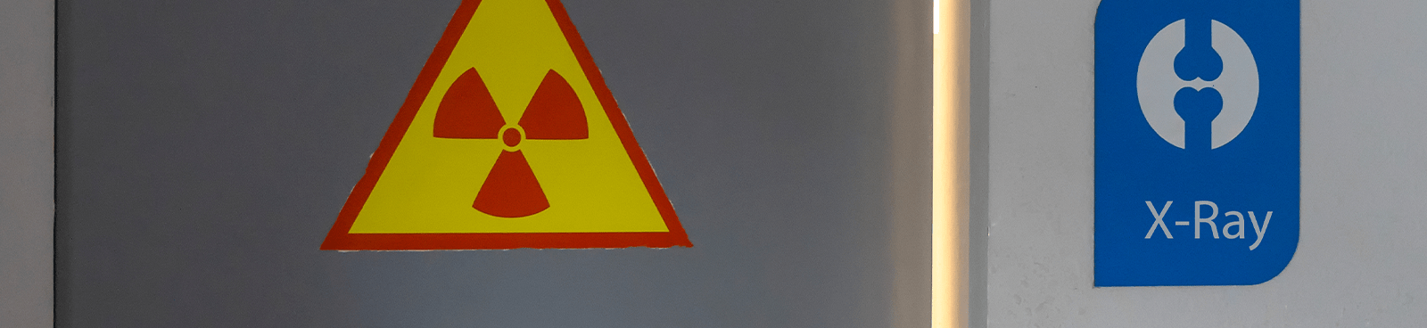 Strahlenschutzkennzeichnung mit dreieckigem Strahlungsgefahrenzeichen und der Aufschrift „X Ray“ an einer Wand einer kontrollierten Anlage