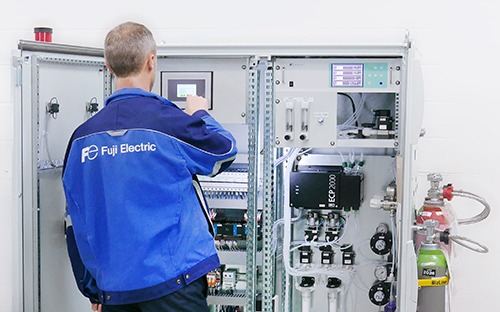 Technician in front of a gas analysis cabinet checking industrial emissions