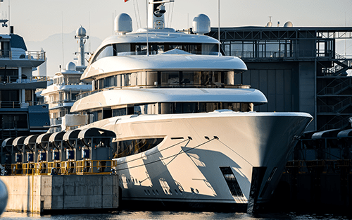 Modern bir limanda demirlemiş büyük lüks yat, pruva, üst üste yerleştirilmiş güverteler ve donanımları gösteren önden görünüm