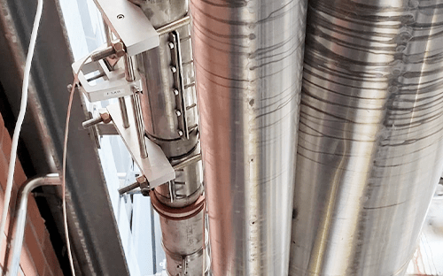 Capteur ultrason non intrusif fixe sur conduite verticale en acier pour mesurer le debit de vapeur en milieu industriel