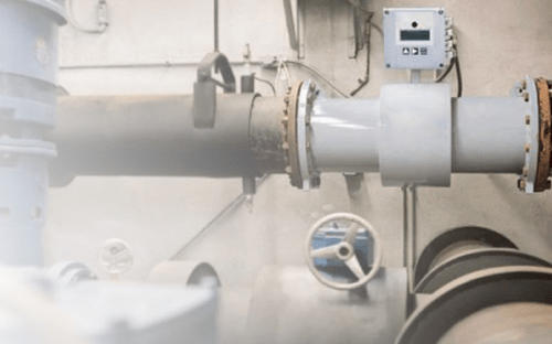 Débitmètre électromagnétique installé sur une canalisation industrielle avec boîtier de mesure et environnement de process en arrière-plan