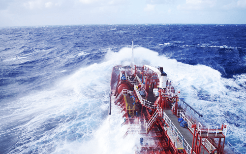 Ein Industrieschiff, das auf hoher See mit rauer See und hohen Wellen auf dem Deck zu kämpfen hat