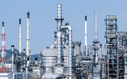 Complexo industrial petroquímico com colunas de destilação, chaminés e redes de tubagens numa refinaria