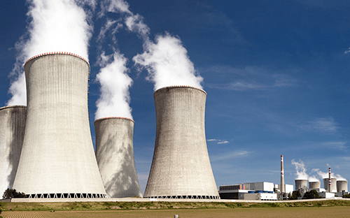 Torri di raffreddamento di una centrale nucleare con pennacchi di vapore che si alzano sopra il sito industriale