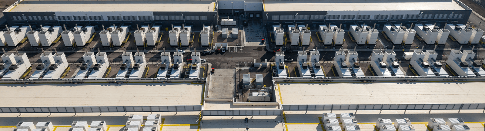 Çatıların üzerine sıralanmış dış teknik üniteleri ve bakım alanlarını içeren bir veri merkezinin havadan görünümü