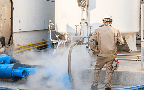 Técnico a intervir numa instalação de gás azoto com reservatório e tubagem industrial, com libertação visível de gás frio