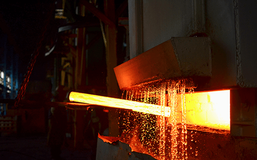 Раскаленный до красна стальной пруток, выходящий из промышленной печи, с разлетающимися искрами во время отбора пробы