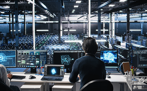 Sunucuların bulunduğu bir veri merkezinde kontrol ekranlarını izleyen ve gerçek zamanlı görüntülemeleri sağlayan teknisyen