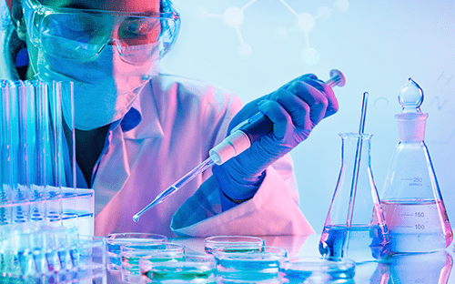 Technicienne de laboratoire manipulant une pipette et des échantillons chimiques sous hotte de sécurité