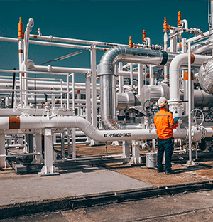 Technicien inspectant un réseau de tuyauteries vapeur sur une installation industrielle de process énergétique