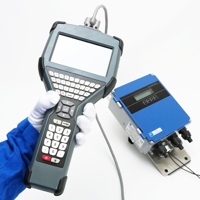 Técnico que utiliza un terminal Pocket HART ATEX conectado a un caudalímetro ultrasónico industrial