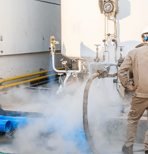 Techniker, der an einer Industrieanlage mit Rohrleitungen und Gasfreisetzung in einer Stickstoffproduktionsanlage arbeitet