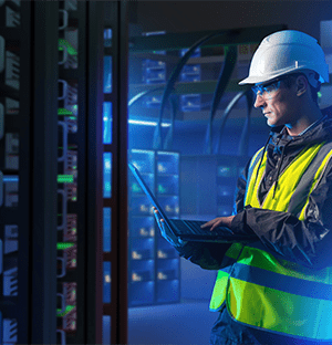 Technicien surveillant des racks serveurs haute densité avec ordinateur portable dans un data center
