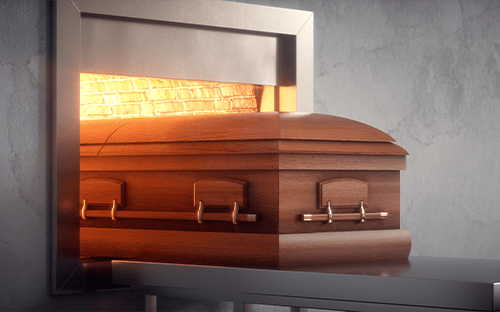 Ataúd de madera introducido parcialmente en un horno de cremación con la cámara de combustión iluminada, en un entorno funerario