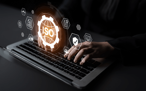 Main utilisant un ordinateur portable avec interface ISO illustrant la conformit&eacute;, la qualit&eacute; et la gestion des normes