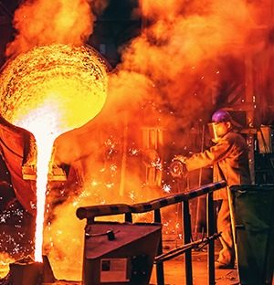 Gießen von geschmolzenem Metall in einer Gießerei mit einem Bediener, der eine Hitzeschutzkleidung trägt