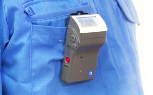 Dosimètre électronique personnel fixé sur la poche d'une veste de travail pour le suivi individuel de l'exposition aux rayonnements