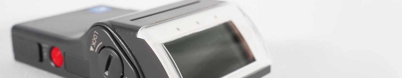 Gros plan d'un dosimètre électronique personnel avec écran LCD et bouton de verrouillage pour le suivi de l'exposition aux rayonnements
