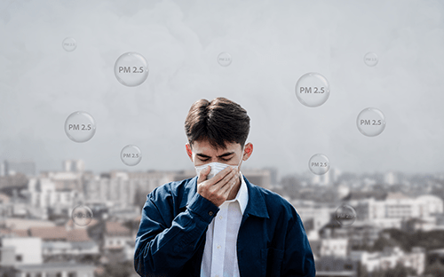 Personne portant un masque devant un paysage urbain avec visualisation des particules fines PM2.5 dans l'air