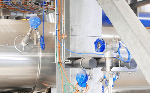 Temperaturfühler und Messgeräte, die an einer Industrieanlage mit Rohrleitungen, Verkabelung und Prozesssensoren montiert sind