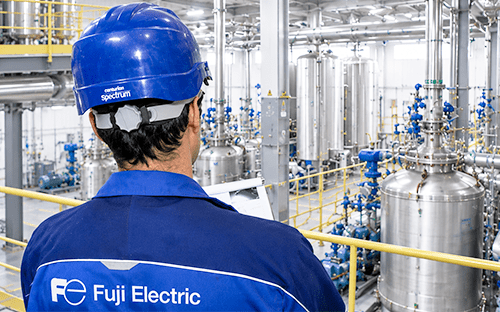 Техник компании Fuji Electric осматривает промышленный объект, оснащенный резервуарами и технологическими трубопроводами, с мостика