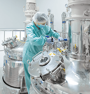 Reinraumtechniker bei der Arbeit an einem Edelstahltank in einer industriellen Produktionsanlage