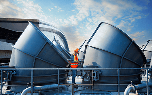Technicien inspectant des tours de refroidissement industrielles sur une installation d&eacute;di&eacute;e &agrave; l'optimisation &eacute;nerg&eacute;tique des proc&eacute;d&eacute;s