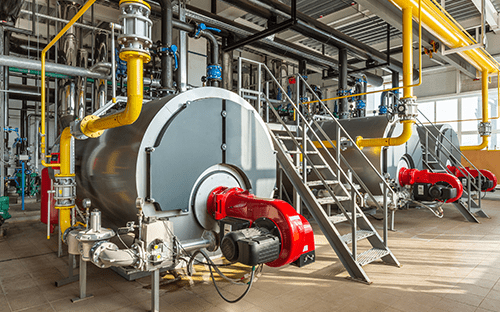 Industriekessel, die mit Brennern ausgestattet und an ein Rohrleitungsnetz in einem Heizraum angeschlossen sind