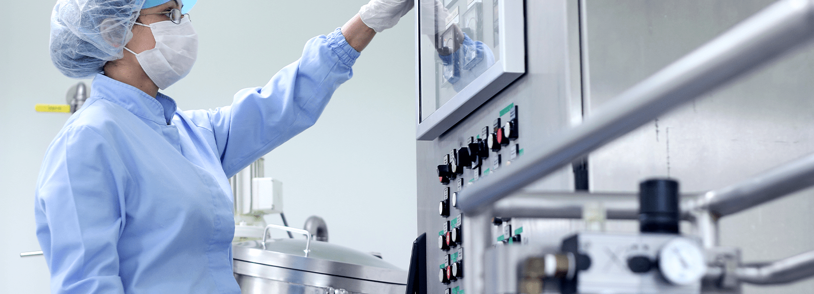 Produktionstechnikerin, die ein Bedienfeld zur Steuerung eines industriellen Prozesses einstellt