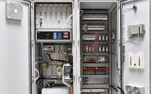 Interior de um armário CEMS com analisador multigás, medidores de caudal e equipamentos elétricos de controlo