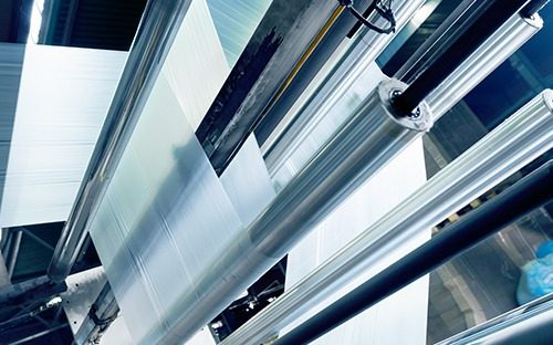 Folienbahn, die in einer industriellen kontinuierlichen Verarbeitungsanlage zwischen Metallwalzen geführt wird