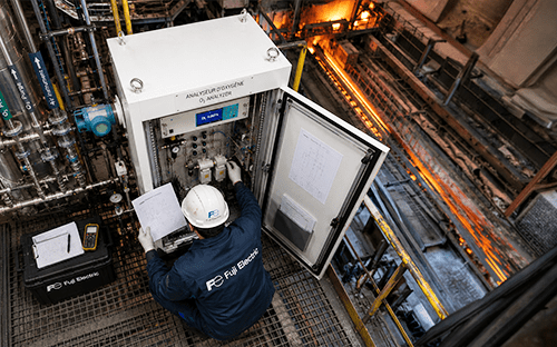 Fuji Electric teknisyeni, yüksek sıcaklıklı bir çelik üretim hattının yakınında bir oksijen analiz kabinini kontrol ediyor