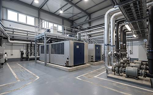 Local technique industriel abritant plusieurs équipements de production thermique, des pompes et un réseau de tuyauteries métalliques
